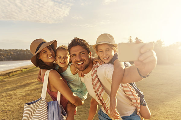 Familia conformada por un hombre, una mujer, y dos niñas, se encuentran en la playa tomándose una selfie de sus vacaciones, gracias a los vuelos económicos para La Guajira que encontraron con Turismo Compensar